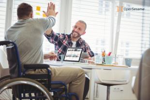 Two business professionals looking at OpenSesame courses and giving one another high fives in the office